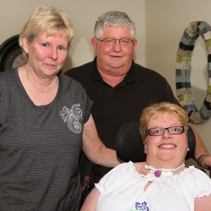 A picture of Chelsey, a young woman who needs chronic mechanical ventilation (CMV), with her parents